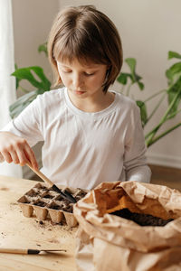 The girl collects soil in peat pots for planting seeds. spring gardening hobby for the whole family.