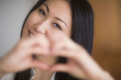 Young woman at home making a heart with the hands