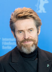 Close-up portrait of smiling mid adult man against blue background