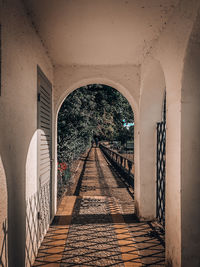 Footpath amidst buildings seen through arch bridge