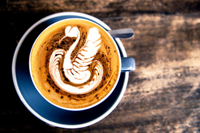 Cup of hot cappuccino on wooden table background. top view of coffee with swan latte art