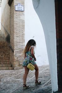 Full length rear view of woman walking against building