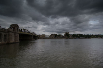 Bridge over river against cloudy sky