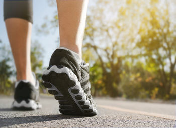 Low section of person wearing shoes on footpath