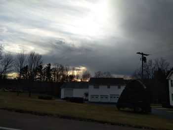 Silhouette trees and buildings on field against sky