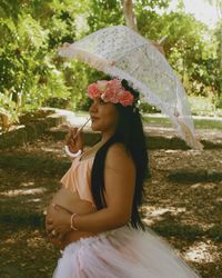Young woman holding umbrella while standing in rain