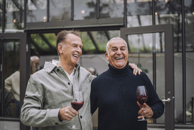 Happy retired male friends with wine enjoying at dinner party