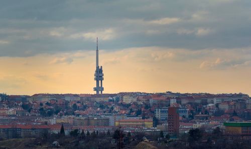 Tower amidst buildings in city against sky during sunset