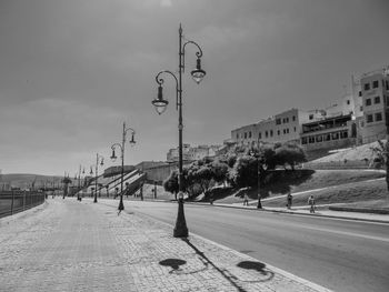 Street lights by road against sky