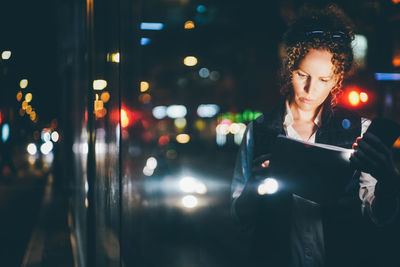 Portrait of young woman in city at night