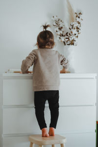 A child small girl stands backwards near white commode