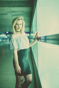 Portrait of young woman standing by window