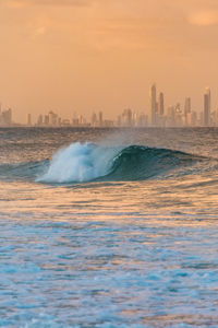 Scenic view of sea and buildings against sky during sunset