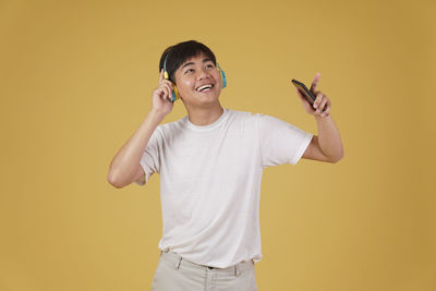 Portrait of a smiling young man against yellow background