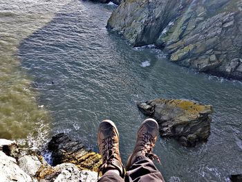 Low section of woman standing on cliff by sea