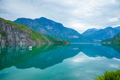 Scenic view of lake and mountains against cloudy sky