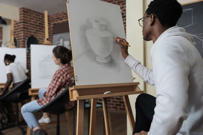 Side view of man drawing on canvas