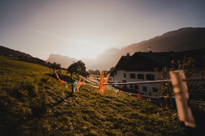 Rear view of woman walking on field against sky during sunset