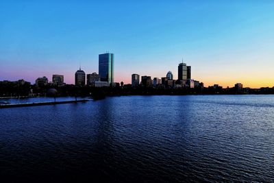 River by buildings against blue sky during sunset