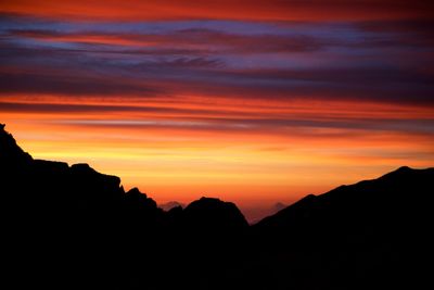 Scenic view of silhouette mountains against orange sky