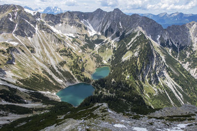 Aerial view of lake amidst mountains against cloudy sky