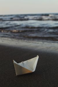 Paper floating on beach against sky