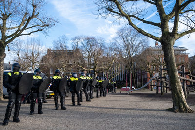 Group of people on street against bare trees in city