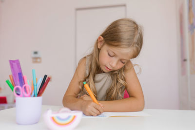 Seven year old girl does her homework while sitting at a table