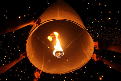 Low angle view of illuminated light bulbs at night