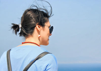 Portrait of young woman looking away against sky