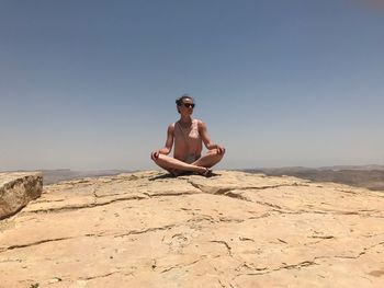 Full length of man sitting on land against clear sky