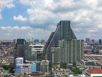 Modern buildings in city against cloudy sky