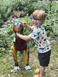 Toddler boy in eyeglasses playing with metal dinosaur sculpture