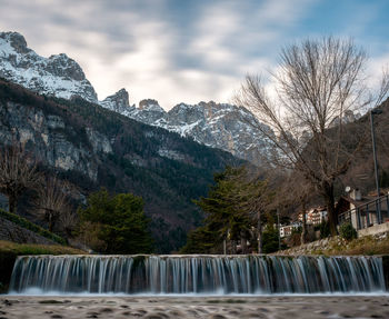 Scenic view of lake by snowcapped mountains against sky