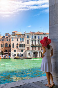 Rear view of woman standing by canal in city