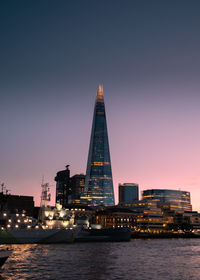 Illuminated buildings in city against clear london sky