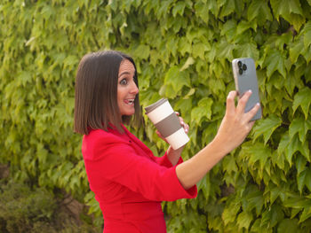 Mature woman taking a funny selfie while drinking coffee