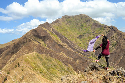 Rear view of man standing on mountain against sky