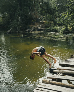 Side view of shirtless man jumping in lake