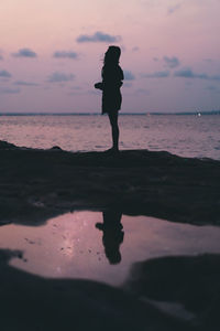 Silhouette person standing on beach during sunset