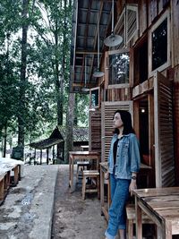 Woman standing by building against trees