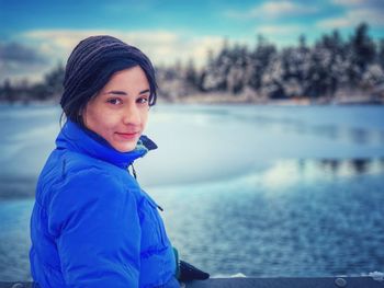 Portrait of smiling woman by lake during winter