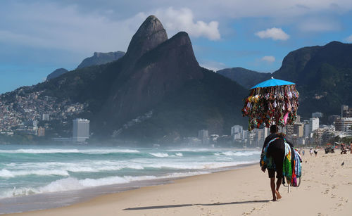 People on beach by mountain against sky