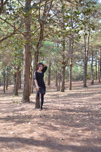 Full length portrait of woman standing in forest