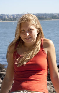 Portrait of smiling young woman standing against sea