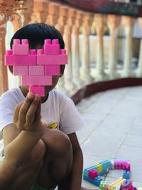 Rear view of boy holding toy while sitting at home