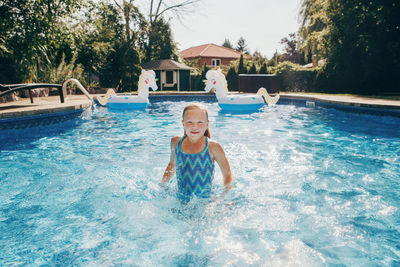Cute adorable girl swimming in pool on home backyard. kid child enjoying having fun in swimming pool