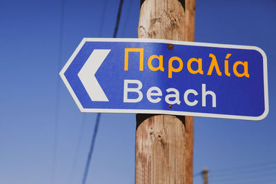 Low angle view of road sign against clear blue sky