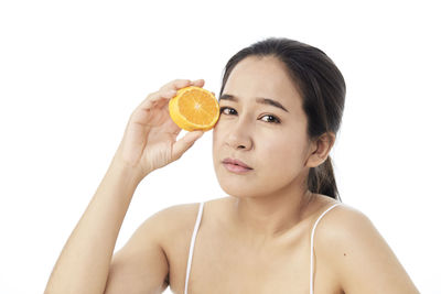 Portrait of young woman holding apple against white background