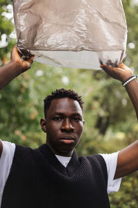 Young african man with plastic over head. plastic pollution concept